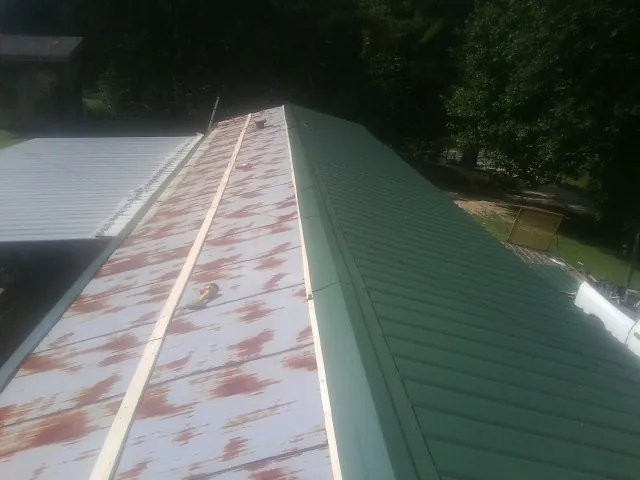 Old rusted panels beside newly installed green metal roofing — Wind Damage Roof Repair by Roofing Brothers in Alvarado