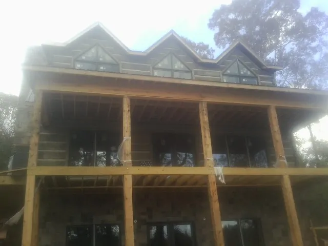 Dormers and porch framing on a large log home under construction — Roof Coating work by our crew in Alvarado