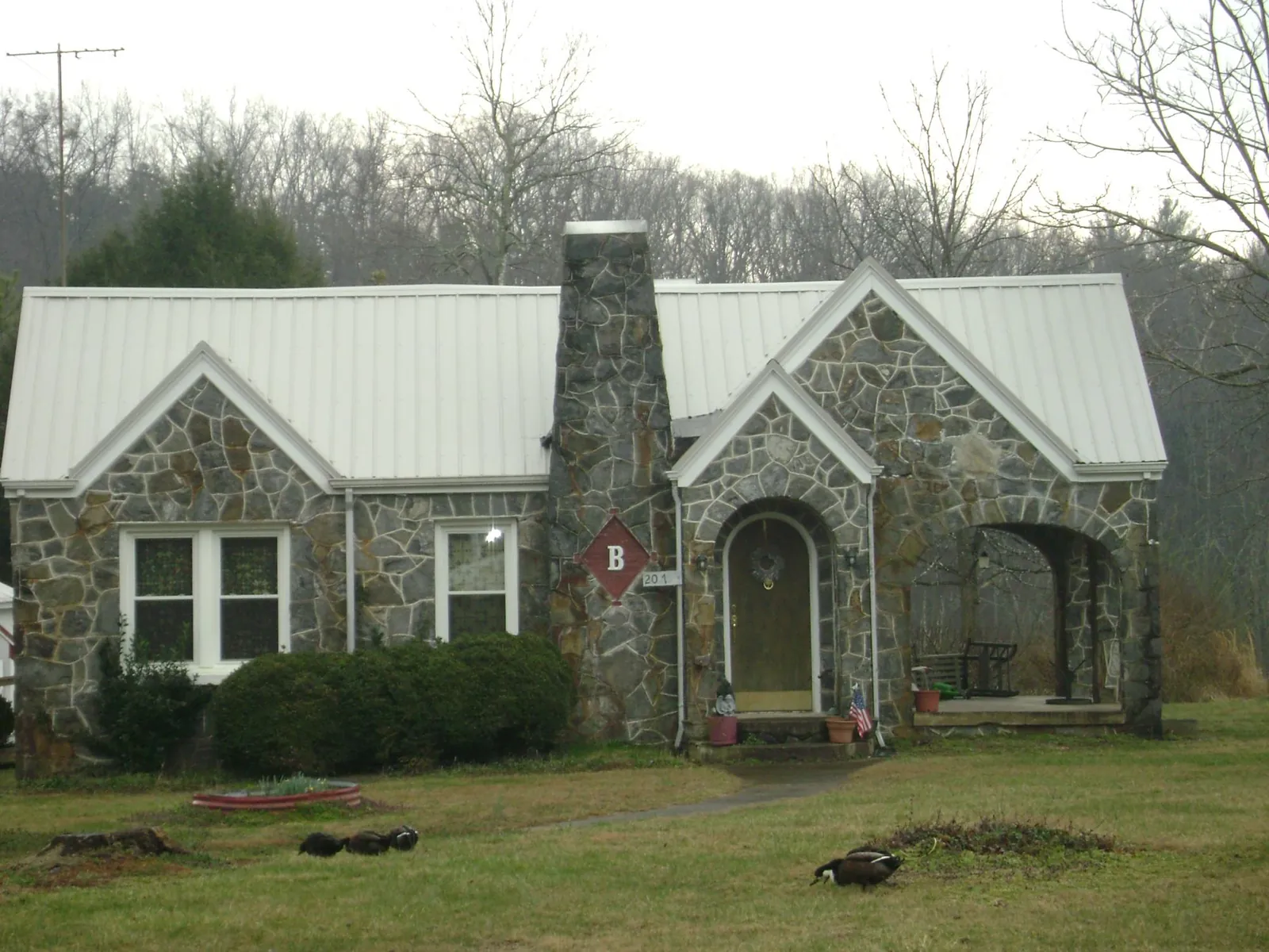White metal roof on a stone cottage with steep gables in Alvarado