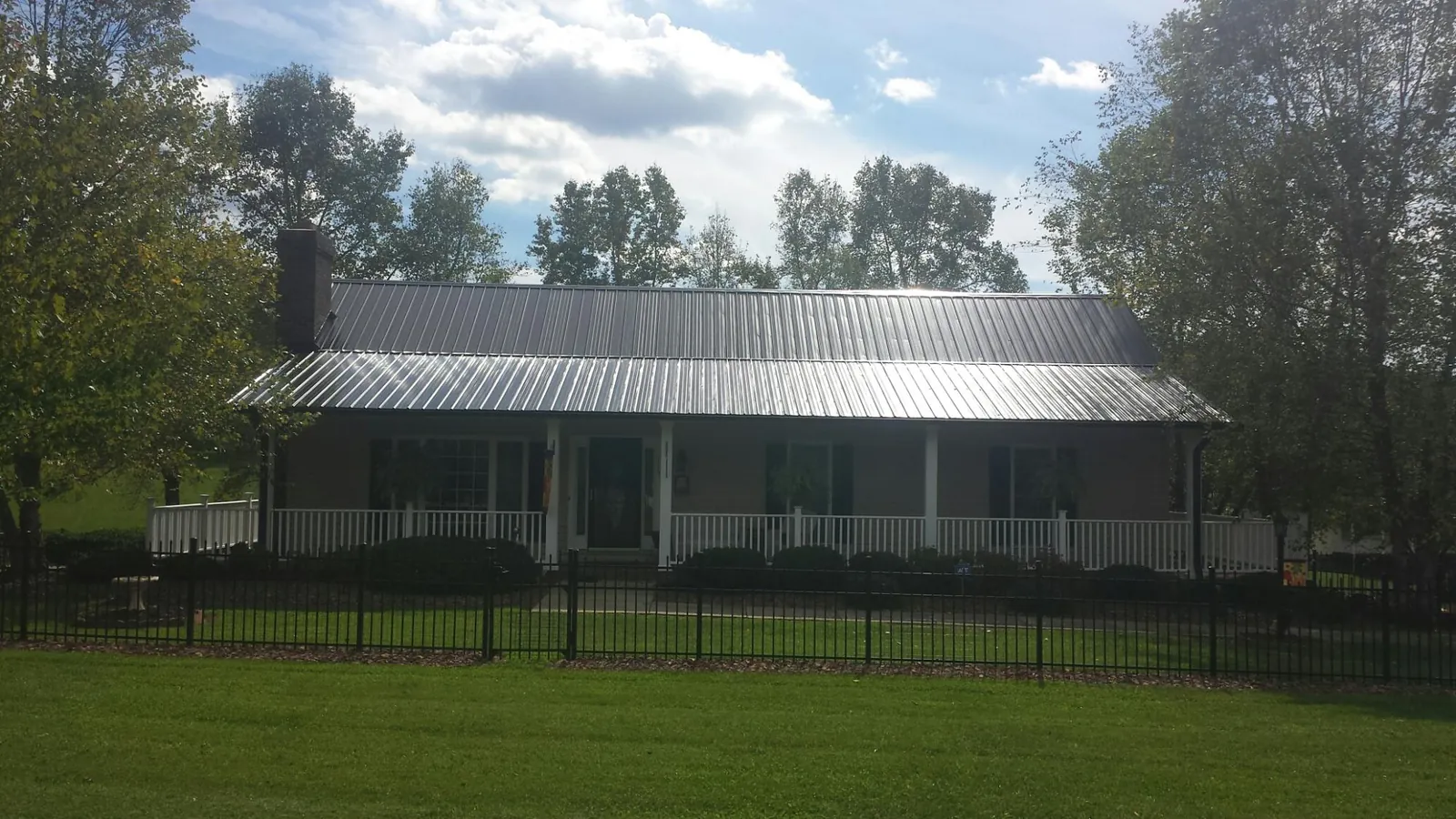 Gray metal roof on a brick ranch with a full width front porch — Gutter Guard Installation work by our crew in Alvarado